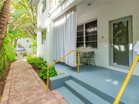 Side view of a two-story house with steps leading to a small patio area.
