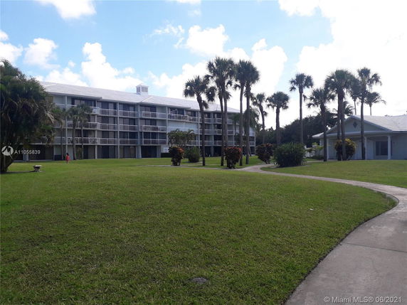 Front view of a multi-story residential building with balconies and a lawn area.