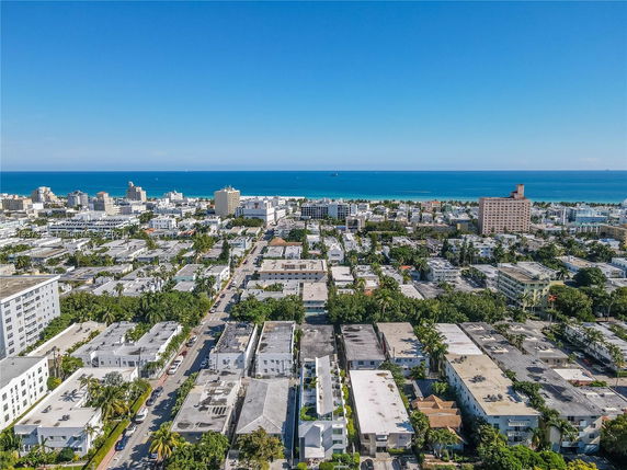 Aerial view of a coastal cityscape with residential and commercial buildings, and the ocean in the distance.