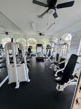 Indoor gym area with fitness equipment and mirrored walls.