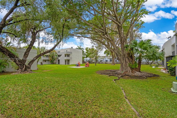 View of residential buildings with a grassy area and trees.