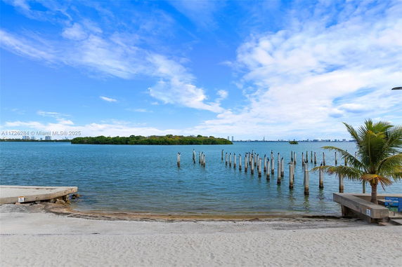 Wide angle view of a waterfront with a dock and distant city skyline.