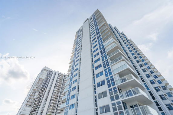 Upward view of a tall residential building with multiple balconies and large windows.