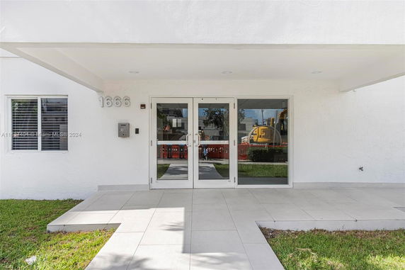 Front view of a building entrance with glass doors and white exterior.