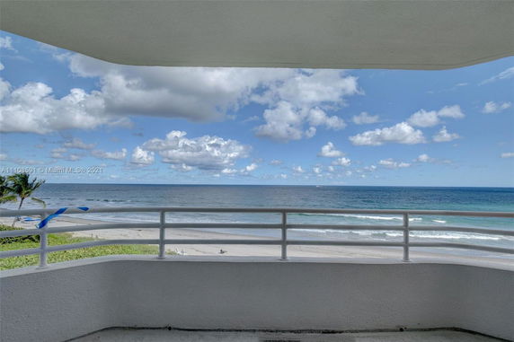 View from a balcony overlooking the ocean and beach.