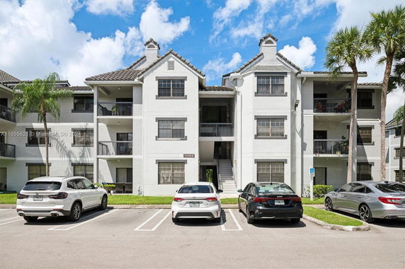 Front view of a multi-story residential building with a parking area in front.