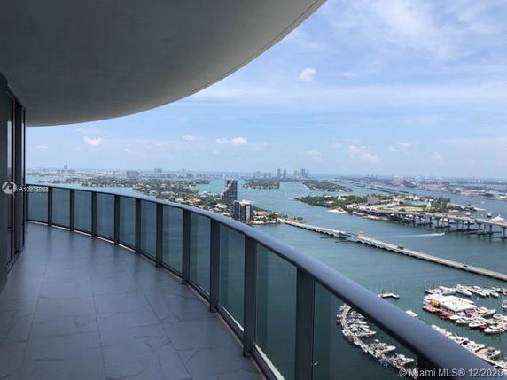 Panoramic view of waterfront and city skyline from a curved balcony.