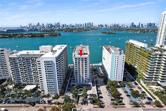 Aerial view of a waterfront cityscape with high-rise buildings and a waterway lined with boats.