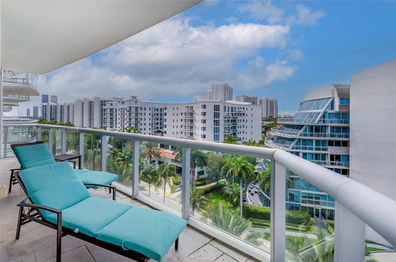Panoramic view from a balcony overlooking modern apartment buildings and palm trees.