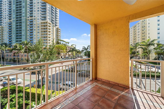 View from a balcony looking towards high-rise buildings and a street with palm trees.