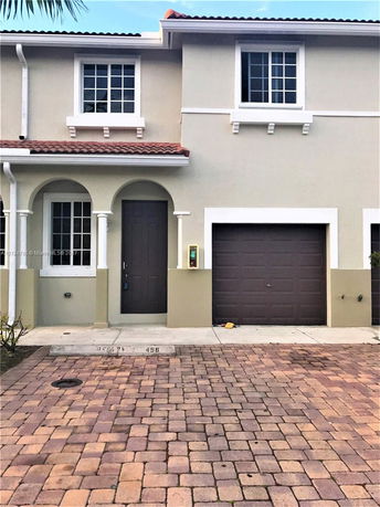 Front view of a two-story house with a brown garage door and a paved driveway.