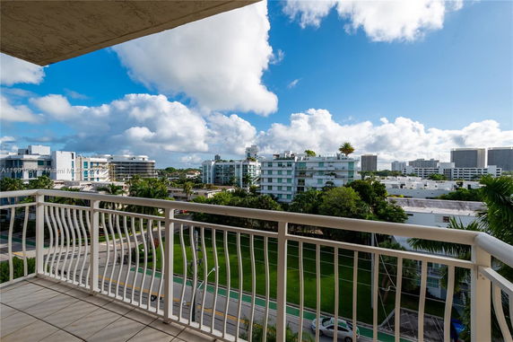 Panoramic view of surrounding buildings and greenery from a balcony.