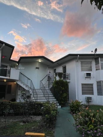 Front view of a two-story residential building with an external staircase and multiple windows.
