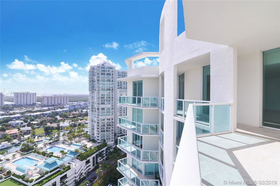 View from a high-rise building with balconies overlooking other tall buildings and a pool area below.