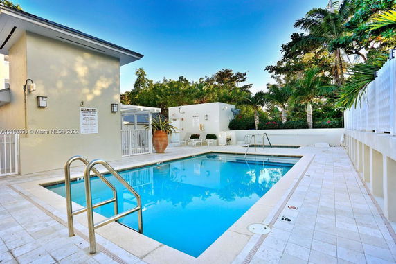 View of a swimming pool area with nearby building structure and surrounding greenery.