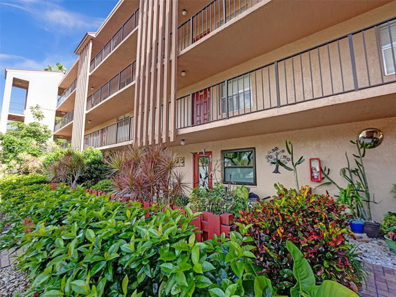 Front view of a multi-story residential building with balconies and exterior plants.