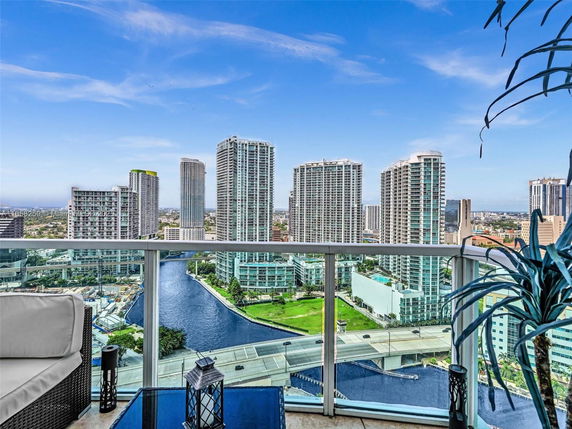 Panoramic view from a high-rise building balcony showing a cityscape with tall buildings and a river.