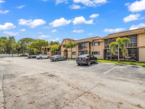 Parking area in front of a two-story building with multiple cars parked.