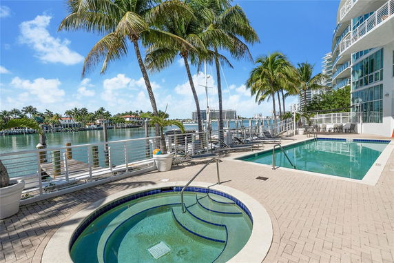 Outdoor swimming pool area with a jacuzzi and waterfront view.