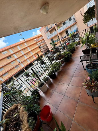 Balcony view of an apartment building courtyard with potted plants.