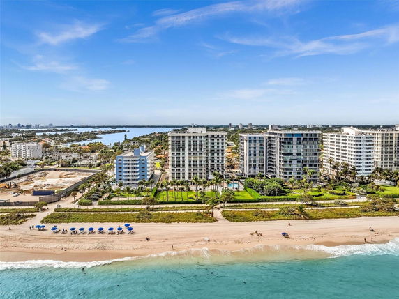 Wide-angle view of multiple beachfront high-rise buildings with a beach and ocean in the foreground.
