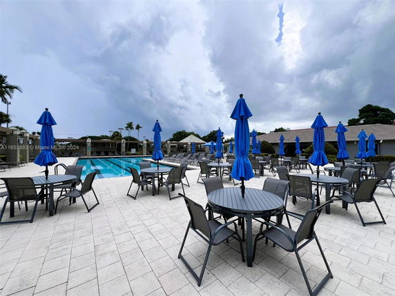 Outdoor swimming pool area with blue umbrellas and patio furniture.