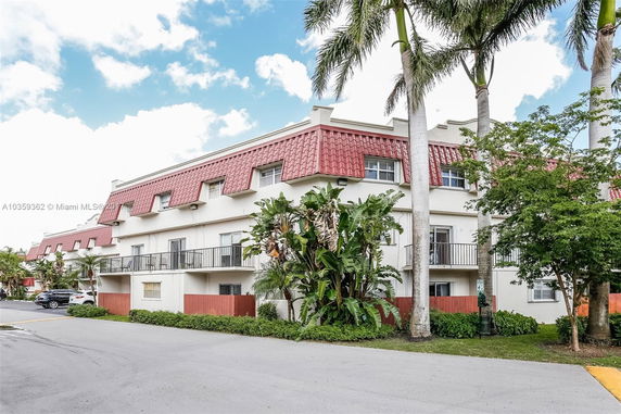 Front view of a multi-story building with red tile roof accents and balconies.