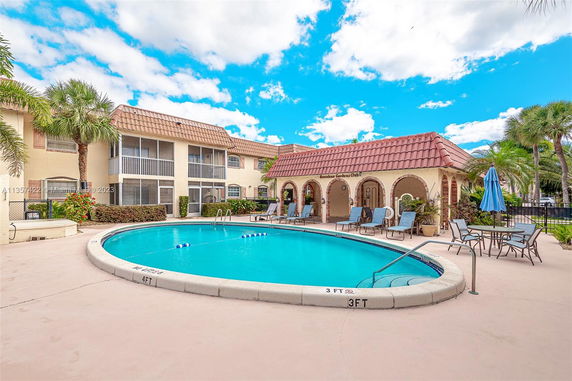 Outdoor view of a swimming pool surrounded by residential buildings with a red tile roof.