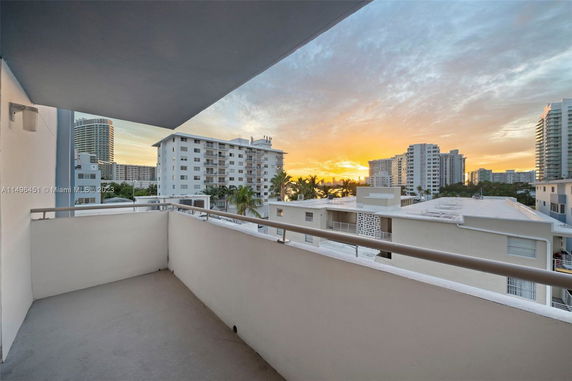 Balcony view overlooking surrounding buildings and sunset.