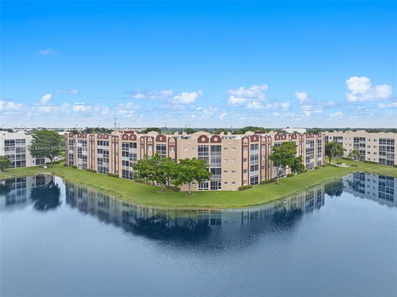 High-rise apartment buildings next to a body of water with surrounding landscape.