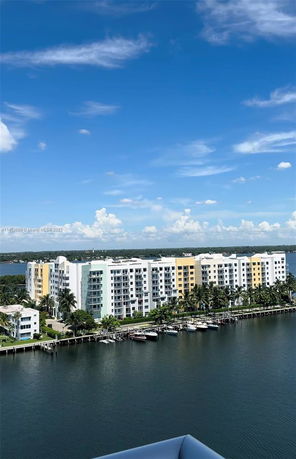 View of apartment buildings by the water with boats docked nearby.