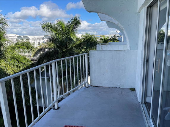 View from a balcony overlooking tropical foliage and nearby buildings.