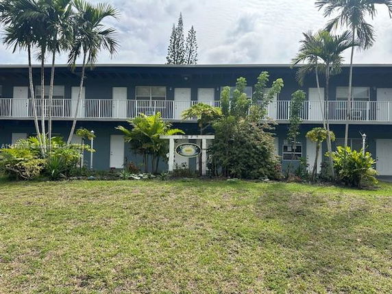Front view of a two-story building with balconies and surrounding greenery.