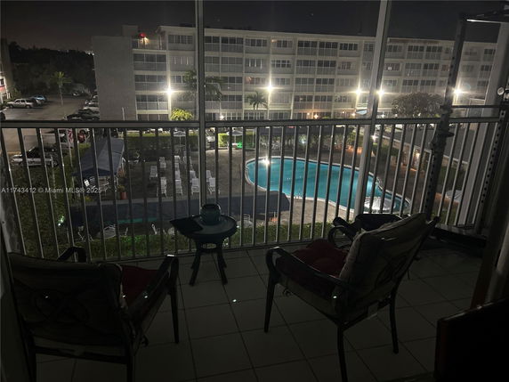 View from a balcony overlooking a swimming pool area at night.