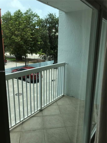 View from a balcony showing a parking area and trees.