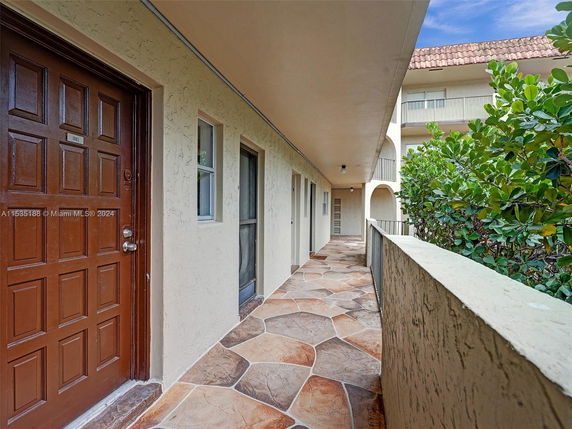 Front view of a building corridor with a tiled pathway and brown door entrances.