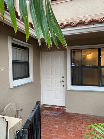 Front view of a house entrance with a white door and adjacent windows.