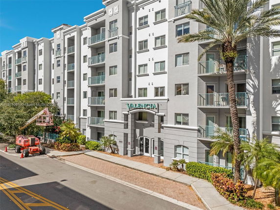 Front view of a multi-story building with balconies and palm trees.