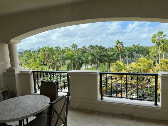 View from a balcony overlooking a lush landscape with palm trees.