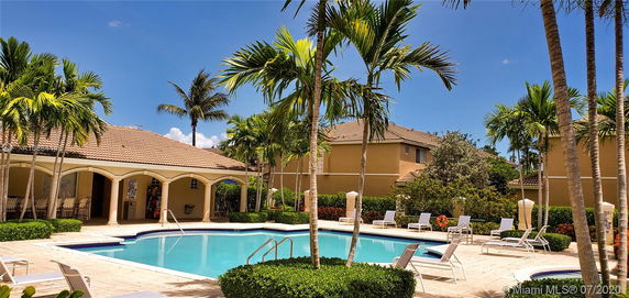 Outdoor swimming pool area surrounded by palm trees and lounge chairs.