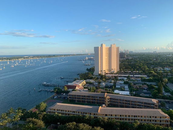 Panoramic view of a tall building and its surrounding areas with a river and boats visible.