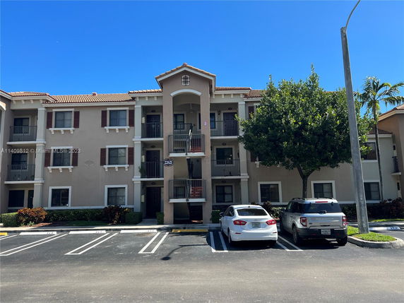 Front view of a multi-story apartment building with a parking area.