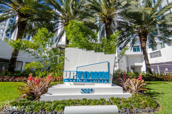 Front view of Uptown Marina Lofts with sign and palm trees.