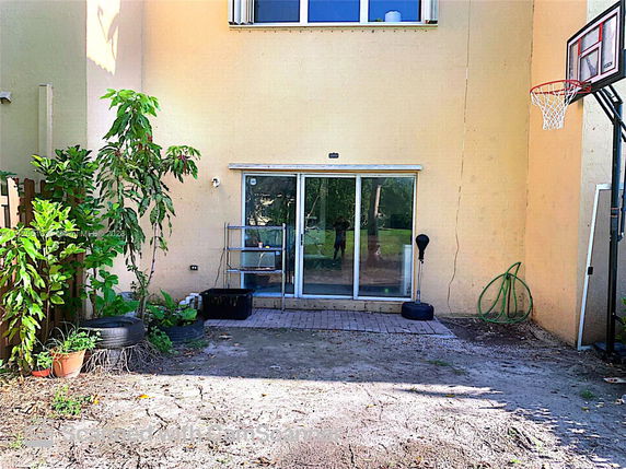 Back view of a two-story house with sliding glass doors and a basketball hoop.