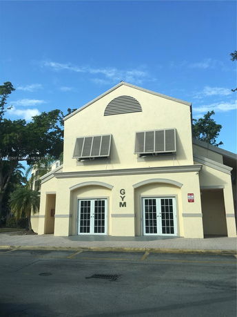 Front view of a gym building with large windows and ventilation grilles.