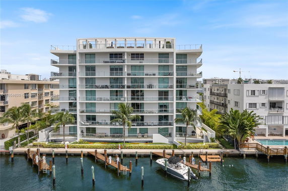 Front view of a multi-story waterfront building with balconies and dock access.