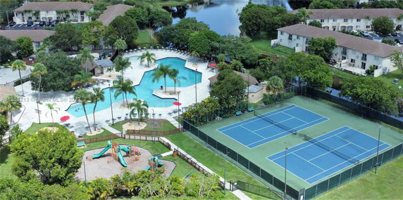 Aerial view of a recreational area with a swimming pool, tennis courts, and a children's playground.