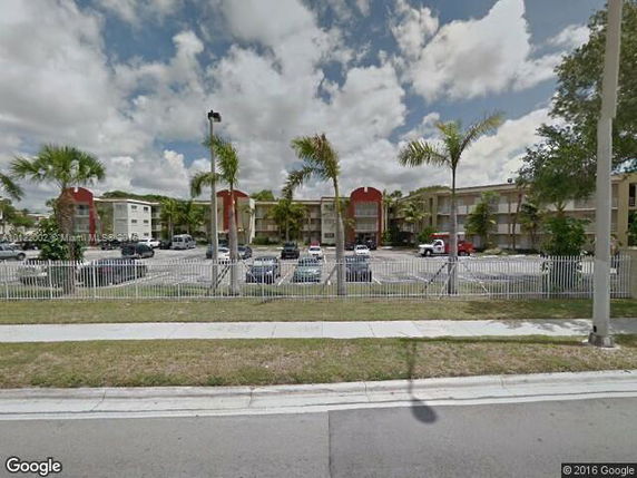 Front view of a multi-story apartment building with parking lot.