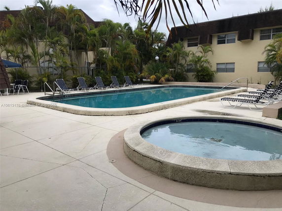 Outdoor area with a swimming pool and lounge chairs surrounded by trees.