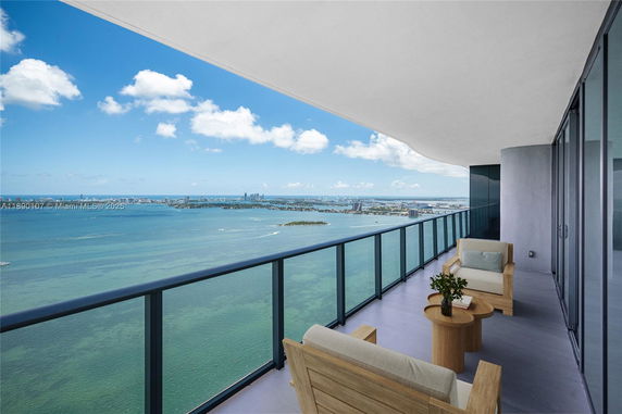 Wide view from a high-rise balcony overlooking a large body of water and distant cityscape.